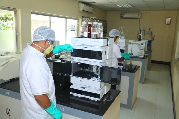 Lab technicians in protective clothing using chromatography equipment