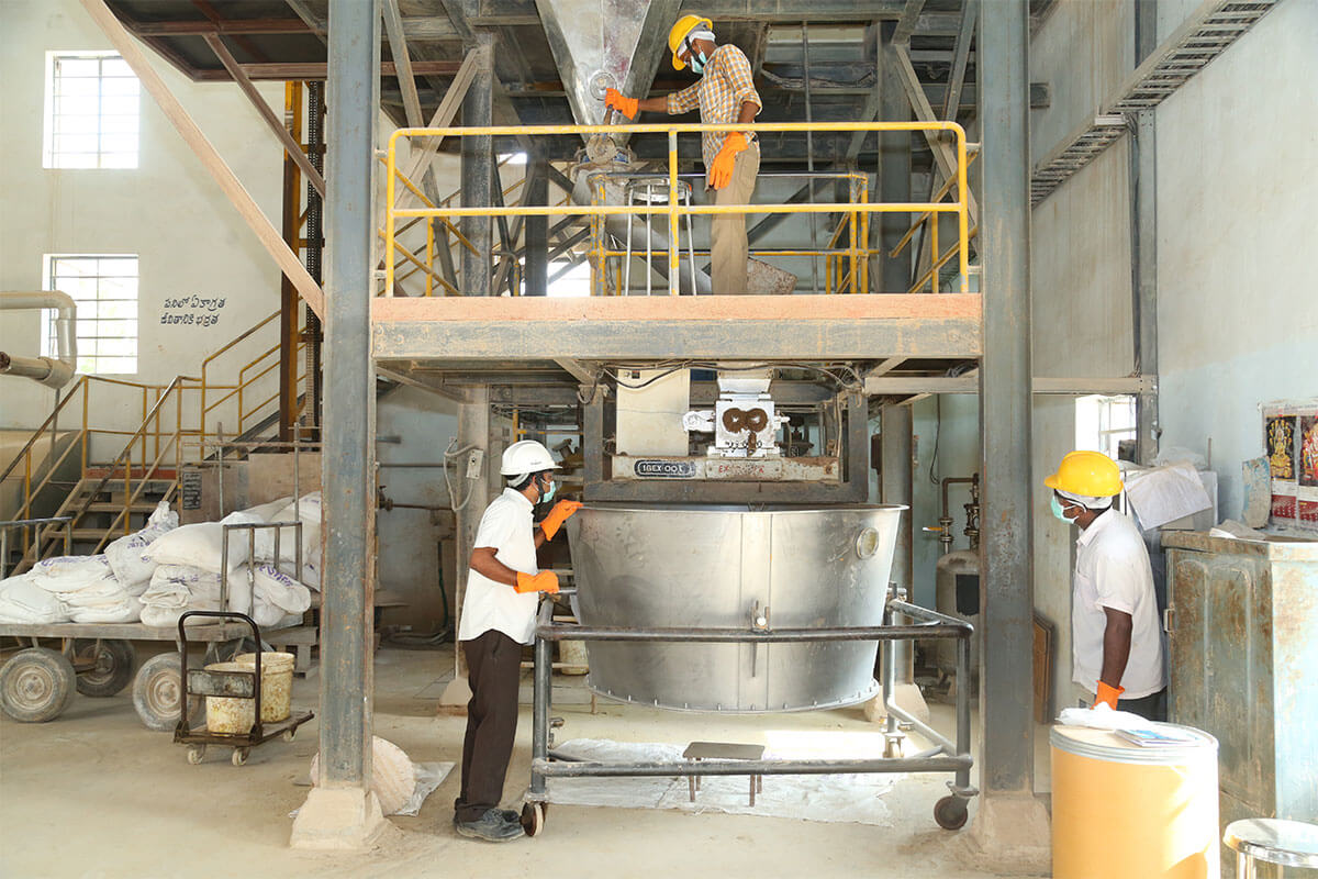 Three workers in a factory setting wearing safety gear, inspecting a large industrial machine.